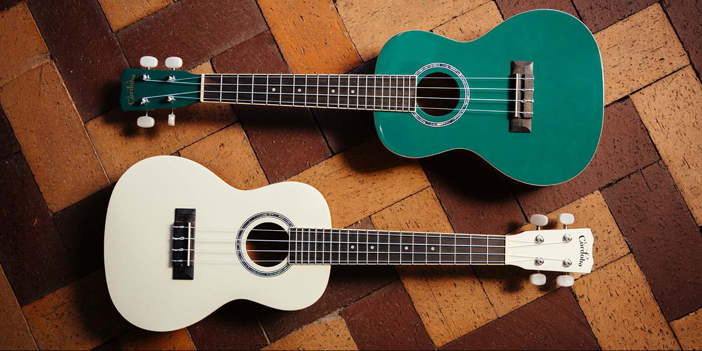 Catalonia Green and Mallorcan Pearl 15C Ukuleles laying on a brick style floor